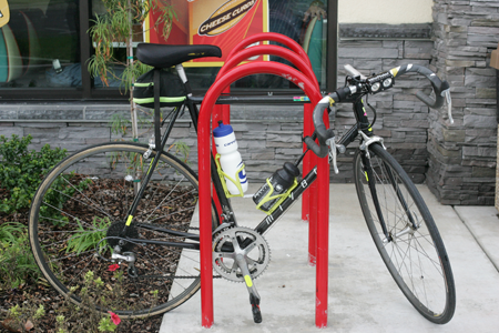 A black bicycle and a black and red bicycle locked to a red